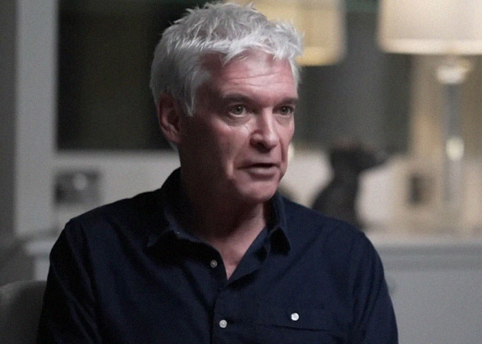 Man in a dark shirt expressing gut feelings during a serious conversation indoors.