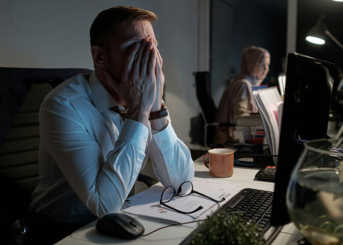 Man at desk covering face with hands, reflecting on unpleasant gut feelings at work.