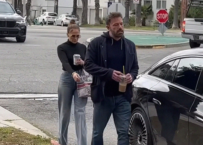 Two people walking with drinks, one holding iced coffee.