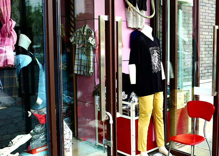 Mannequin behind a glass door wearing a black shirt and yellow pants, shop setting suggests gut feelings about shopping choices.