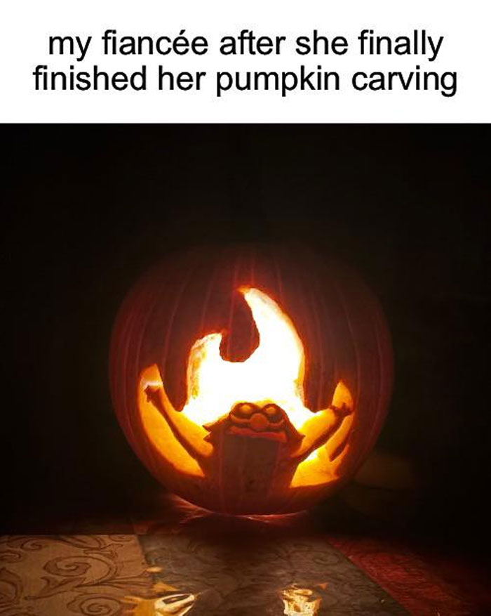 A carved pumpkin resembling the Elmo fire meme, with Elmo's arms raised in flames. Text above reads, "my fiancée after she finally finished her pumpkin carving."