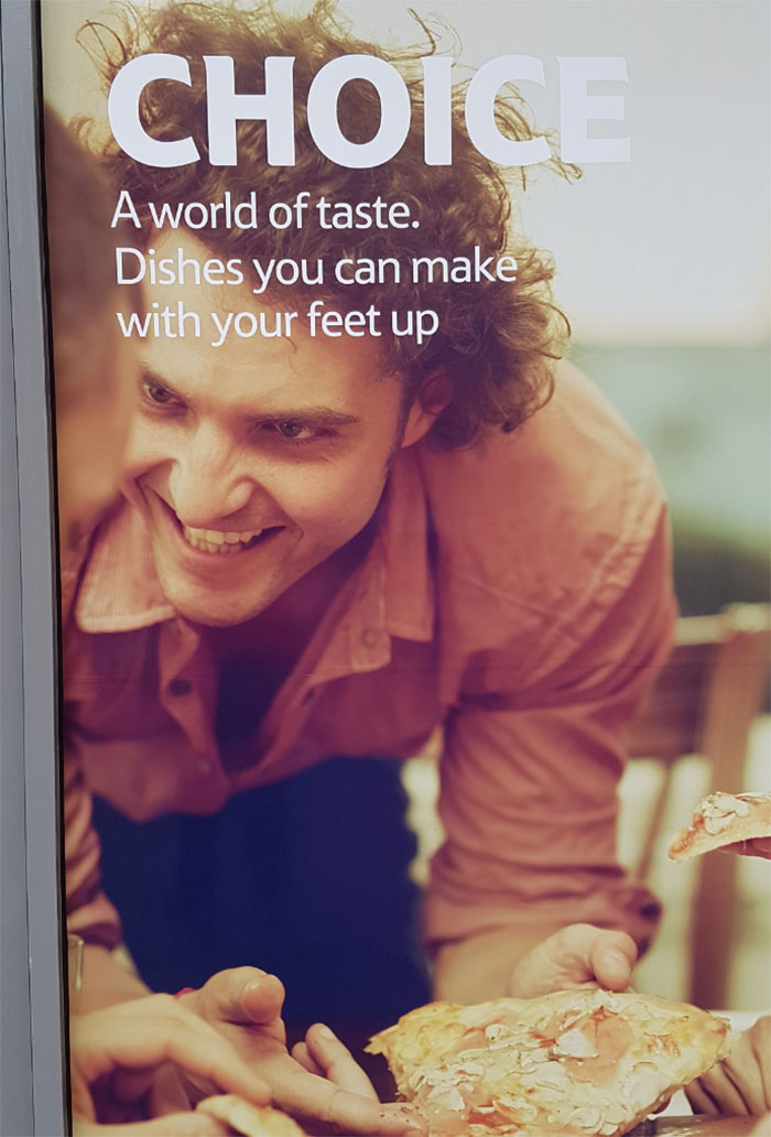 Smiling man holding pizza slice in an ad with awkward slogan, representing funny ad fails.