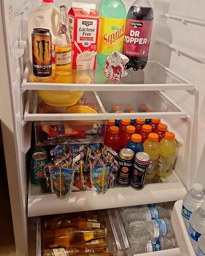 Fridge filled with assorted drinks, alcohol, and snacks, showcasing typical 'dude fridge' contents.