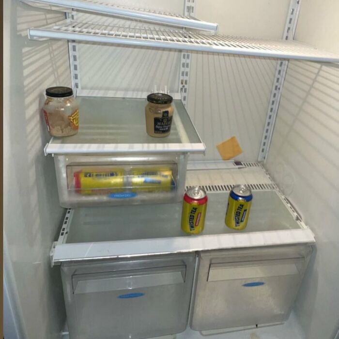 Inside a nearly empty ‘dude fridge’ featuring jars, cans, and minimal food items.