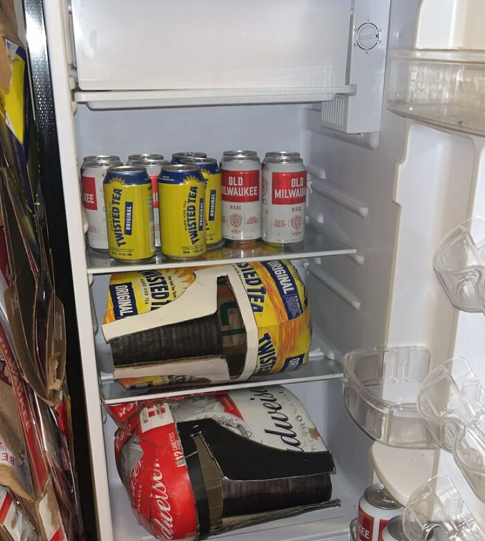 Cans of Twisted Tea and Old Milwaukee stacked in a fridge, representing chaotic dude fridges.