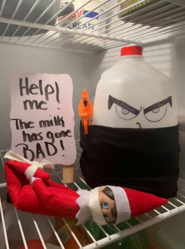 "Elf On The Shelf idea with an elf in the fridge holding a 'Help me! The milk has gone bad!' sign, with a milk jug decorated to look menacing."