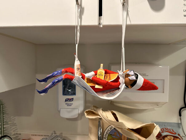 "Elf On The Shelf idea with the elf lounging in a 'hammock' made of a face mask, holding mini bottles, mimicking a relaxed vacation scene."