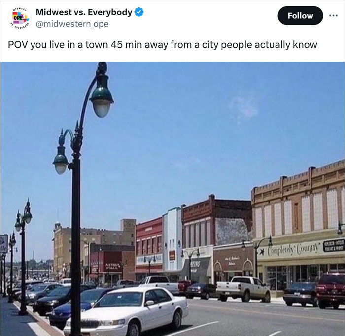 Street view of a small Midwest town with parked cars and historic buildings on a sunny day.