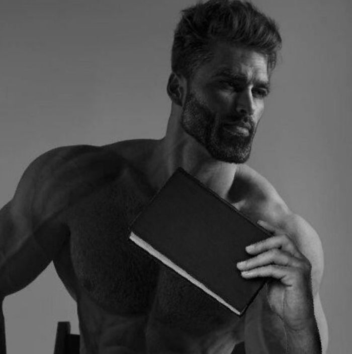 A grayscale image of a muscular man associated with the Giga Chad meme, holding a book with a thoughtful expression.