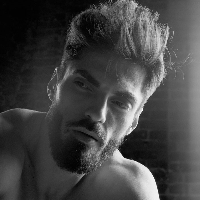 A grayscale close-up of a man's face with a sharp jawline, styled hair, and a beard, representing the Giga Chad meme aesthetic.