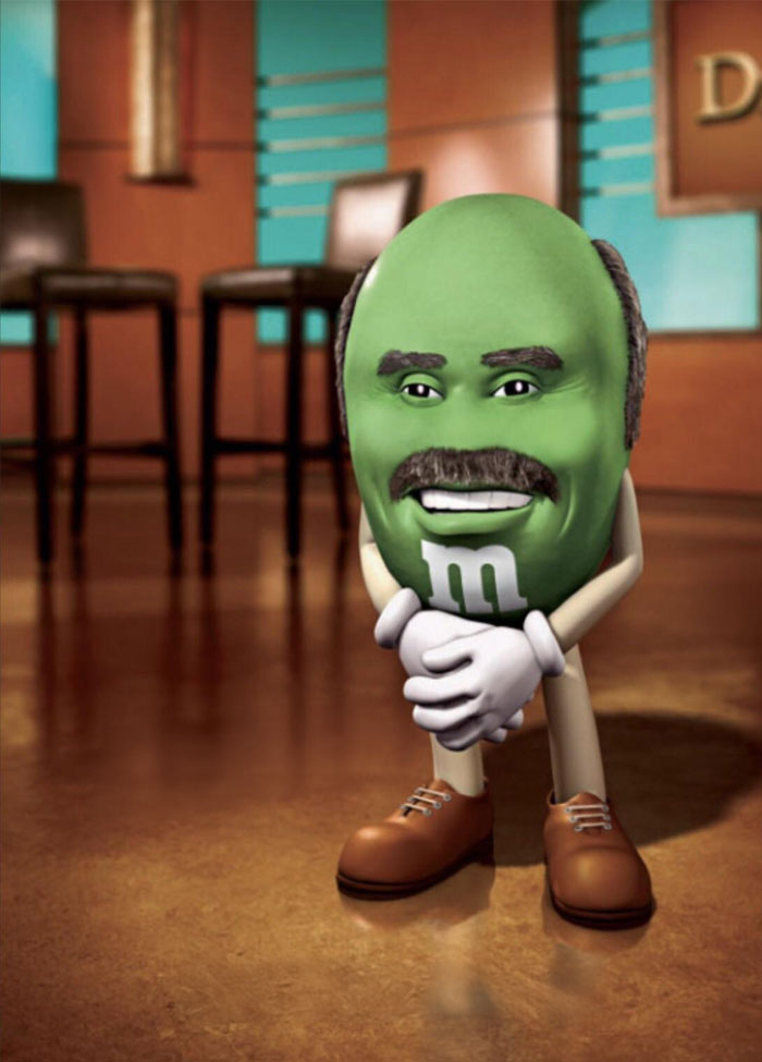 "A goofy ahh meme of a green M&M character with a man's face, mustache, and hair, standing with hands clasped in a studio setting."