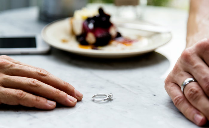 Wedding ring on a table between two hands, symbolizing an attempted manipulation called bluff.