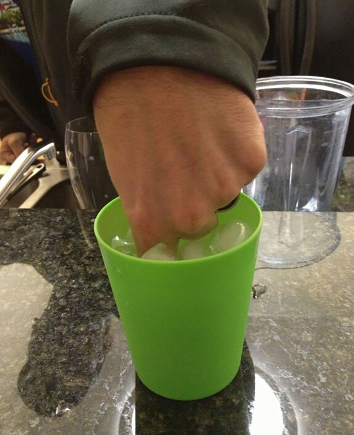 A hand reaching into a green cup filled with ice cubes, illustrating a typical infuriating boyfriend or husband moment.