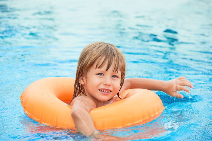 Child in orange float enjoying solo time in pool.