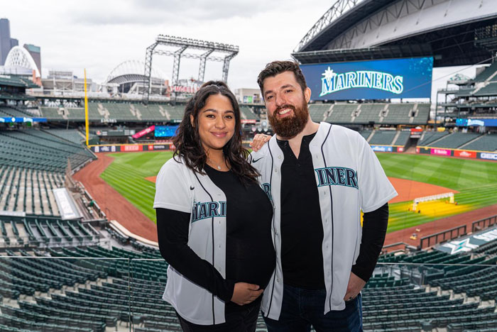 Couple in Mariners baseball jerseys posing at stadium, representing "Love Is Blind" couples.