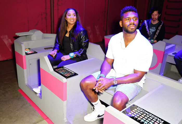 Two individuals from "Love Is Blind" seated in an interactive gaming setup, smiling and engaged.