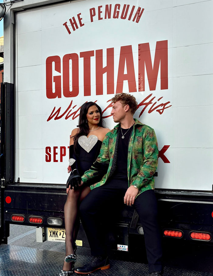 Couple from Love Is Blind sitting together outdoors, smiling, with building signage in the background.