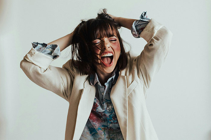 Woman in distress pulling hair, expressing shock and chaos.