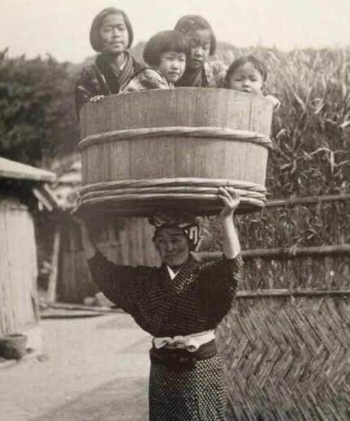 A Japanese Woman Carrying Her Children In A Bucket On Her Head, Japan 1900s