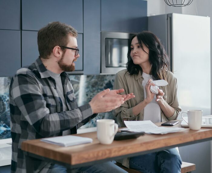 Woman frustrated with partner\'s lack of commitment, sitting at kitchen table having an intense discussion.