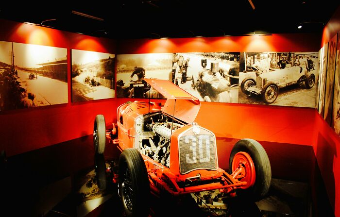 Vintage race car displayed in an opulent home setting, indicating wealth.