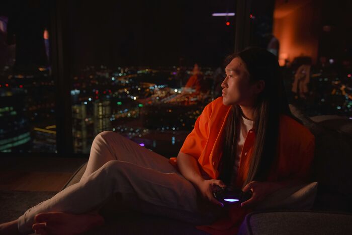 Person enjoying a gaming session in a luxurious home with a stunning night city view.