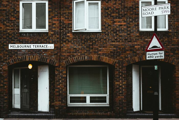 Brick building on Melbourne Terrace, hinting luxury wealth with arched doors and signage.