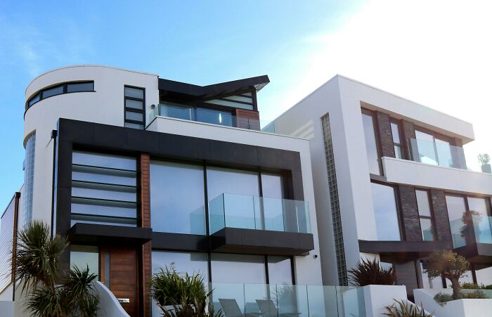 Modern luxury home exterior with large glass windows and sleek design, indicating wealth.