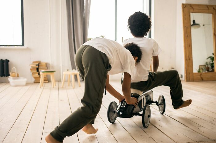 Two kids playing with a toy car on wooden floor, evoking fun and laughter, reminiscent of the funniest joke told to this day.