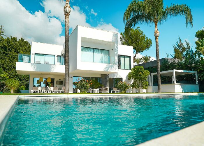 Luxury home exterior with pool, showcasing wealth and sophistication in a lavish setting.