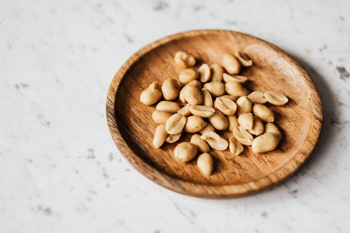 “Wooden plate with peanuts on a marble countertop, related to funniest joke discussions.”