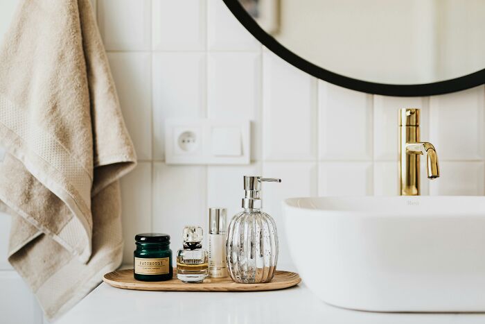 Luxury bathroom vanity with designer toiletries and gold faucet, suggesting wealth.