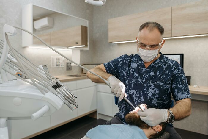 Dentist with mask examines patient, highlighting body alterations concerns in a clinical setting.