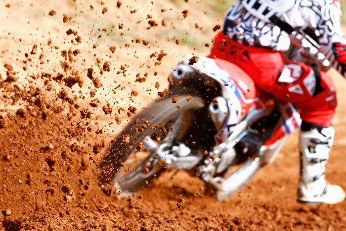 Motocross rider speeding on dirt track, illustrating dynamic movement and action.