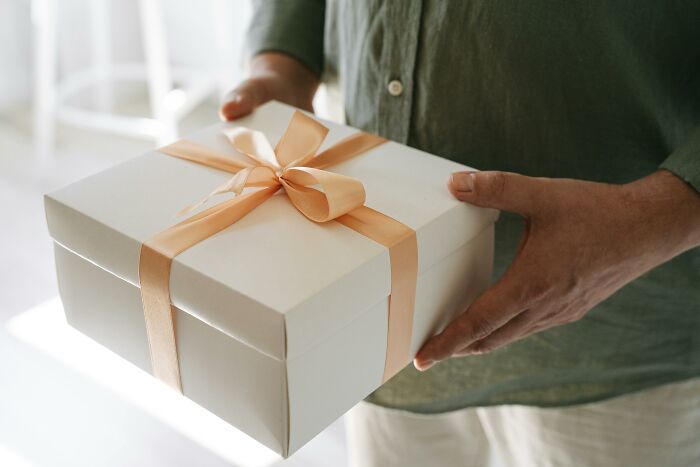 Person holding a gift box tied with a peach ribbon, featuring relationship decision context.