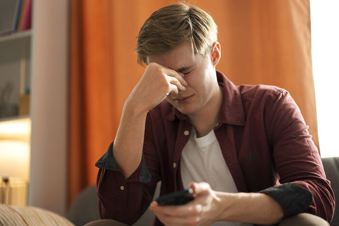 Man holding phone, looking stressed, experiencing doubts about marrying this person.