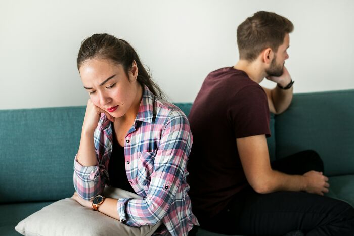 Couple on a couch, visibly upset, illustrating a moment questioning marriage decisions.