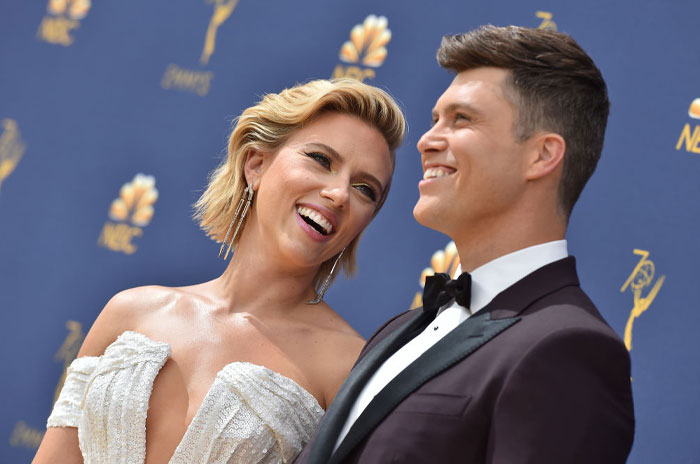 Scarlett Johansson and her husband, Colin Jost, smiling together on the red carpet at an awards event, dressed in formal attire.