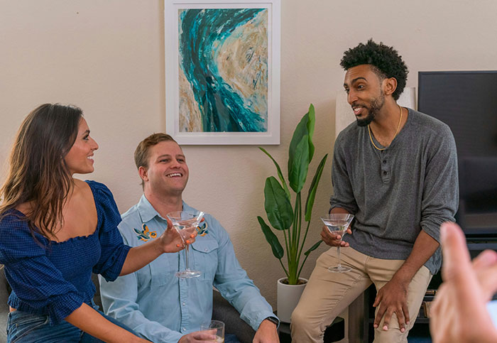 Three people talking and holding drinks, illustrating signs of marriage challenges in a casual setting.