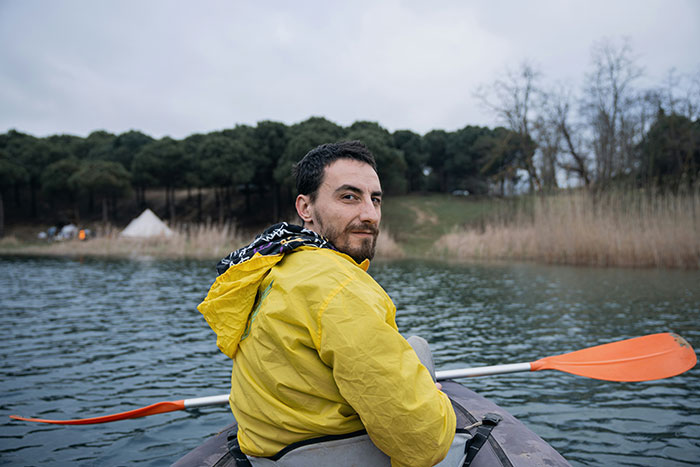 Man in a yellow jacket kayaking on a serene lake, representing advice on signs of a marriage destined to fail.