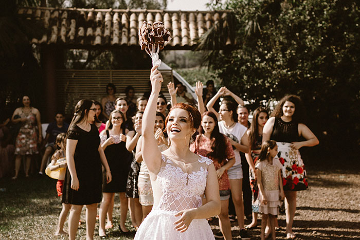 Bride throwing bouquet at wedding with guests eagerly watching, hinting at marriage's potential signs of failure.