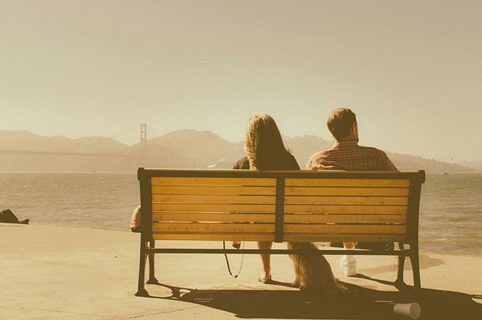 A couple sits on a bench by the waterfront, a sign their marriage may be destined to fail.