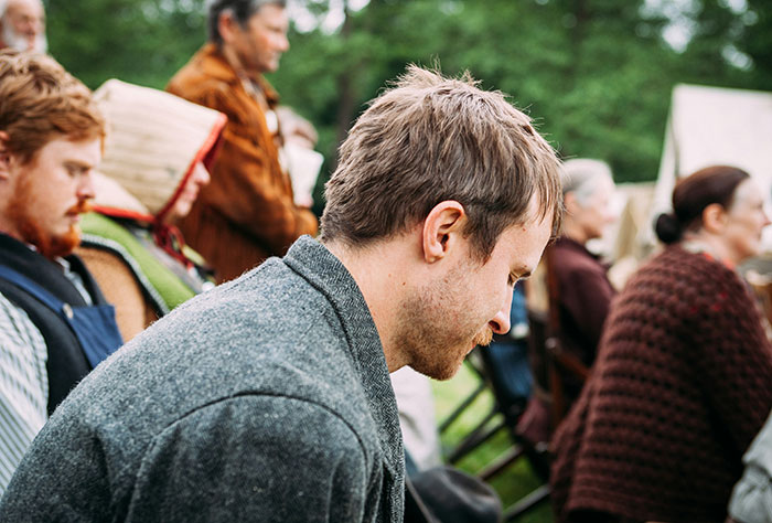 A man in a pensive mood at an outdoor gathering, reflecting on signs a marriage may be destined to fail.