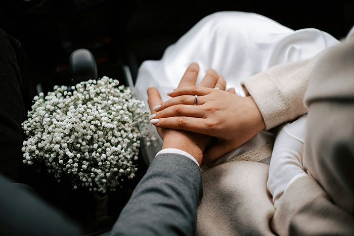 Couple holding hands near wedding bouquet, symbolizing struggles older people say predict marriage failure.