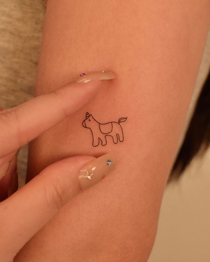 Minimalist unicorn tattoo on a woman's arm, showcasing subtle tattoo ideas for women.