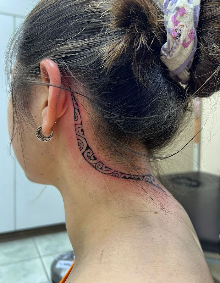 A tattoo idea for women with a woman with a subtle ear and neck tattoo design, showcasing a daring style.