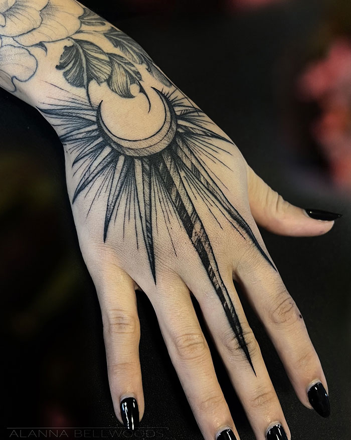 Hand tattoo featuring a crescent moon and rays, showcasing tattoo ideas for women.