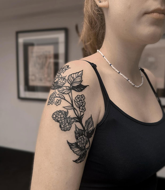 A woman's shoulder with a floral tattoo design, showcasing tattoo ideas for women.