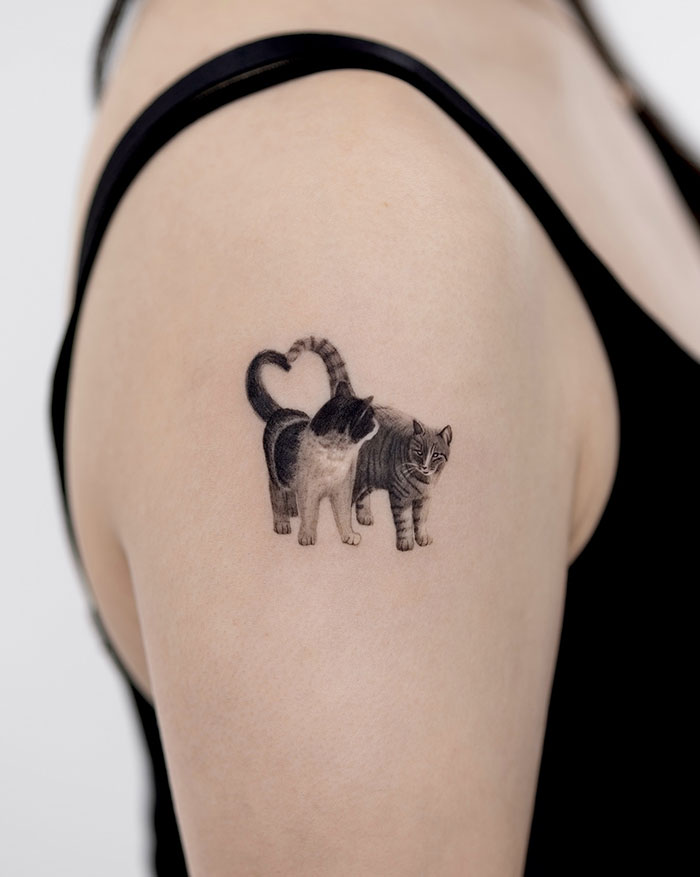 A tattoo idea for women with a cat tattoo on woman's shoulder, showcasing daring and subtle design elements.