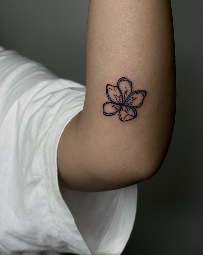 Delicate flower tattoo on a woman's arm, showcasing subtle tattoo ideas for women.